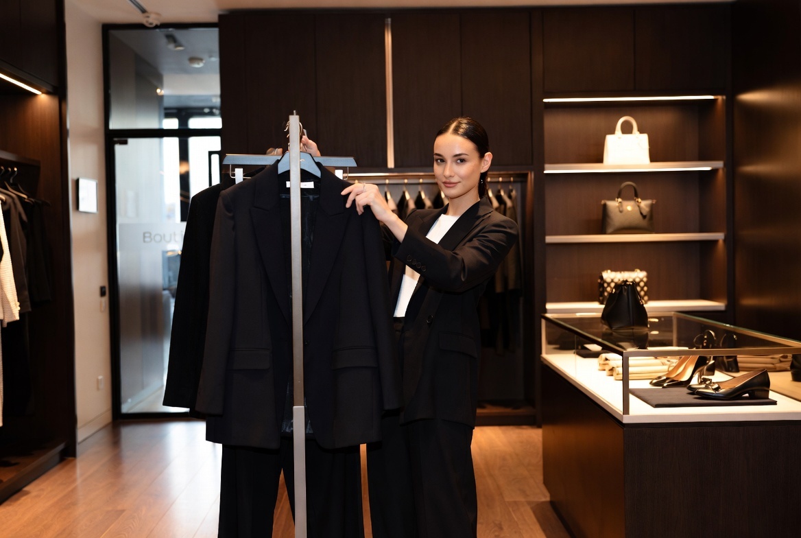 Luxury retail professional in modern boutique with designer fashion and handbags, representing the future of personalized luxury retail consultation