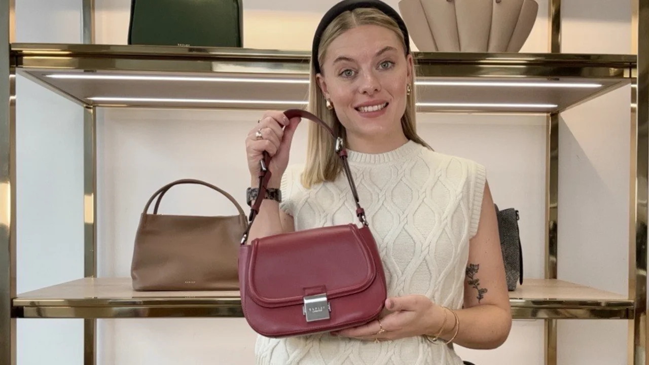 A Radley host holding a red shoulder bag on the shop floor during a live show.